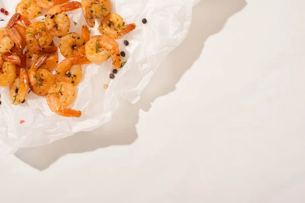 Vue du haut des crevettes frites sur papier parchemin avec poivre sur fond blanc — Photo de stock