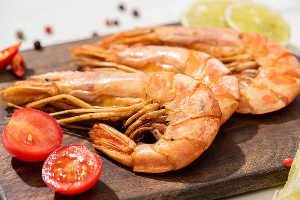 Close up view of fried shrimps on wooden board with cherry tomatoes and lime — Stock Photo