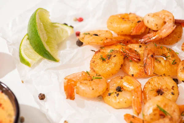 Close up view of fried shrimps with lime and pepper on white parchment paper — Stock Photo