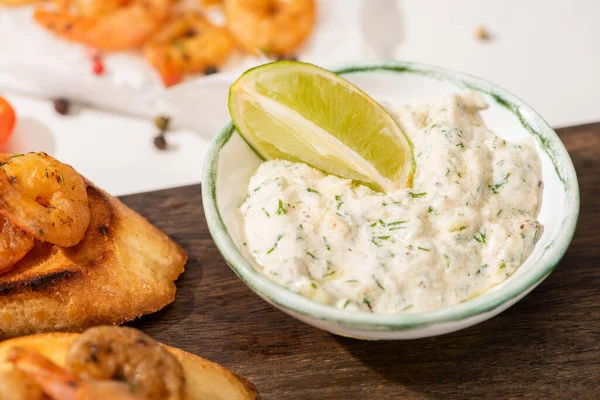 Vista de cerca de canapé con camarones fritos con salsa, lima sobre tabla de madera - foto de stock