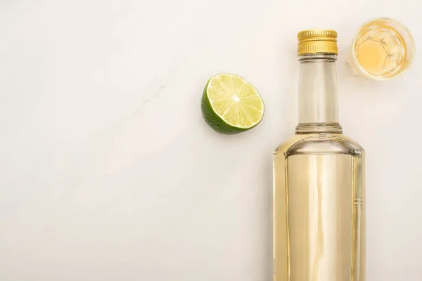 Vista superior da tequila dourada com limão na superfície de mármore branco — Fotografia de Stock