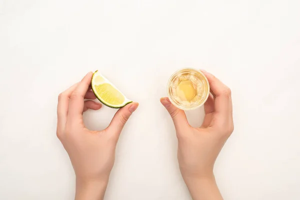 Cropped view of woman drinking golden tequila with lime on white background — Stock Photo