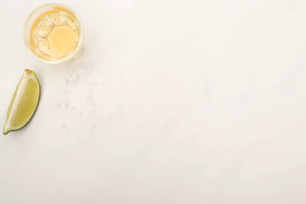 Vue de dessus de la tequila dorée avec de la chaux sur la surface de marbre blanc — Photo de stock