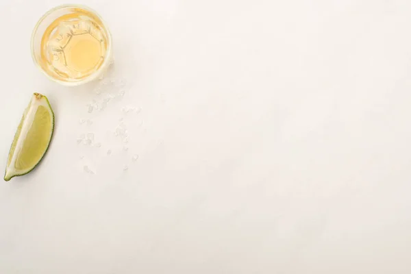 Vista dall'alto di tequila dorata con calce su superficie di marmo bianco — Foto stock