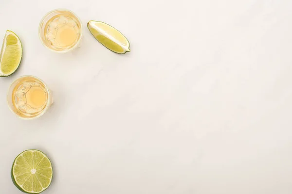 Vue de dessus de la tequila dorée avec de la chaux sur la surface de marbre blanc — Photo de stock