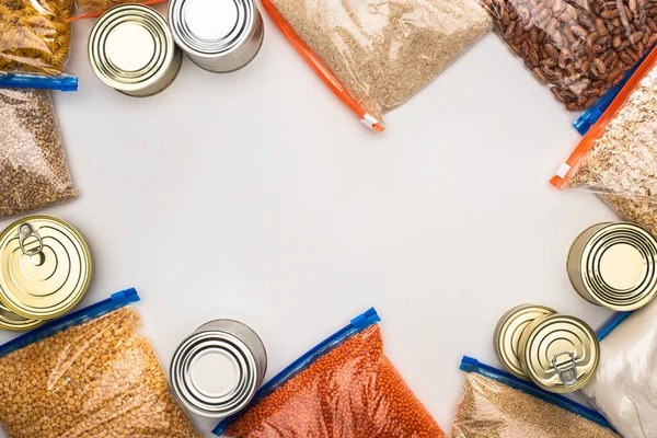 Vista superior de latas e grumos em sacos de zíper no fundo branco, conceito de doação de alimentos — Fotografia de Stock