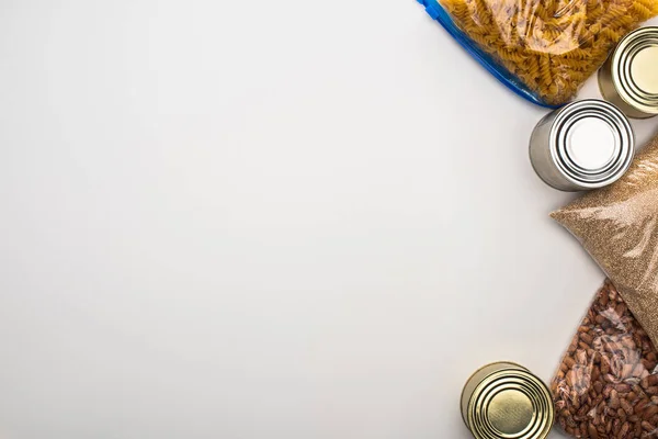 Vista superior de latas e grumos em sacos de zíper no fundo branco, conceito de doação de alimentos — Fotografia de Stock