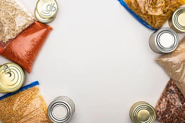 Top view of cans and groats in zipper bags on white background, food donation concept — Stock Photo