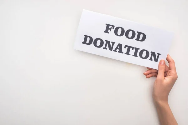 Cropped view of woman holding card with food donation lettering on white background — Stock Photo