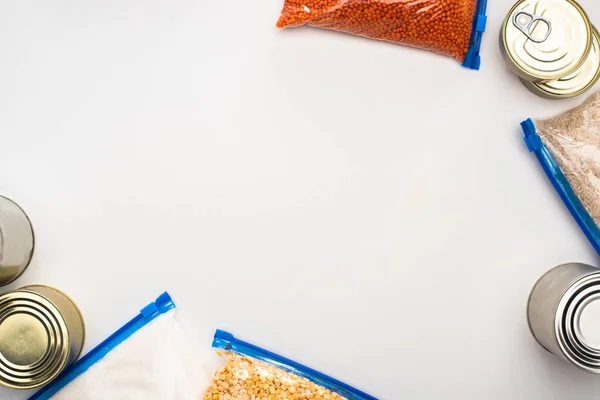 Top view of cans and groats in zipper bags on white background, food donation concept — Stock Photo