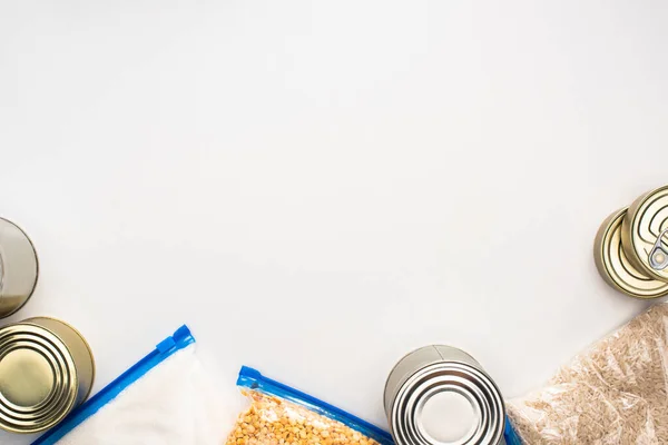 Draufsicht auf Dosen und Grütze in Reißverschlusstaschen auf weißem Hintergrund, Konzept der Lebensmittelspende — Stockfoto