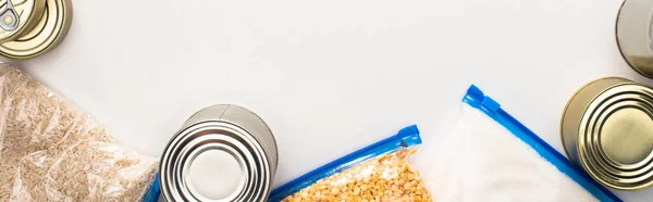 Vista superior de latas e grumos em sacos de zíper no fundo branco, conceito de doação de alimentos — Fotografia de Stock