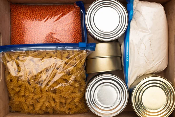 Top view of cans and groats in zipper bags in wooden box — Stock Photo