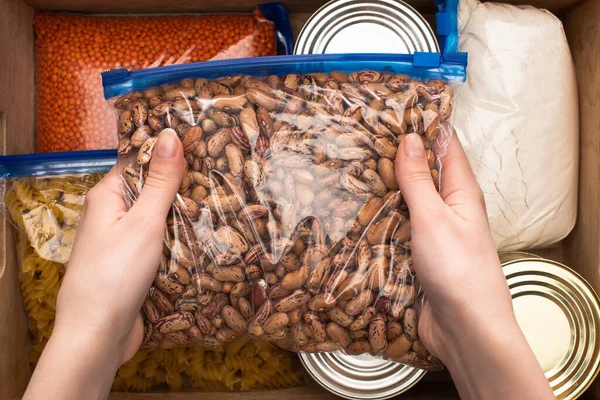 Vista ritagliata della donna che tiene i fagioli nella borsa della chiusura lampo, concetto di donazione di cibo — Foto stock