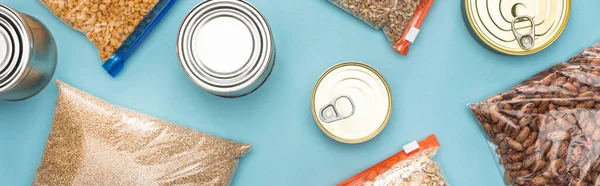 Top view of cans and groats in zipper bags on blue background, food donation concept — Stock Photo