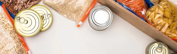 Ansicht von Dosen und Grütze in Reißverschlusstaschen mit Holzkiste auf weißem Hintergrund, Konzept der Lebensmittelspende — Stockfoto