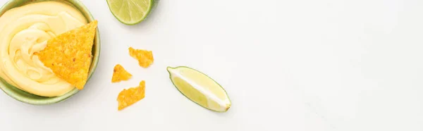 Vue du dessus des nachos de maïs avec sauce au citron vert et fromage sur fond blanc, panoramique — Photo de stock