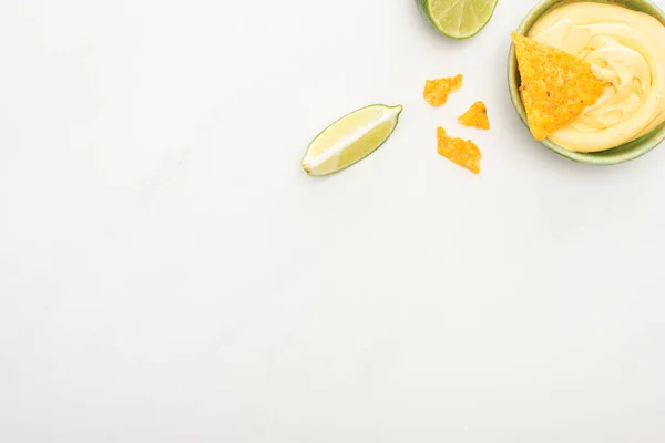 Vue du dessus des nachos de maïs avec sauce au citron vert et fromage sur fond blanc — Photo de stock