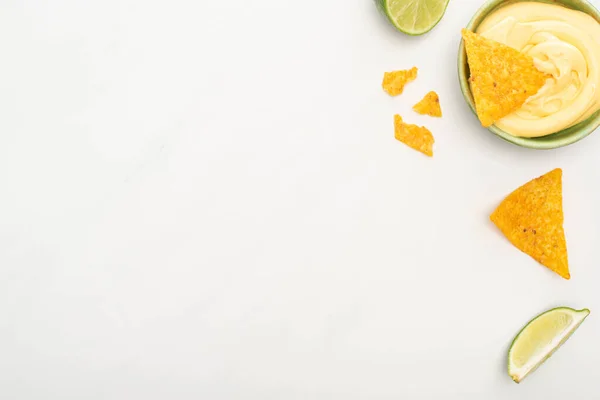 Vue du dessus des nachos de maïs avec sauce au citron vert et fromage sur fond blanc — Photo de stock