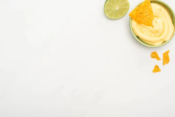 Vue du dessus des nachos de maïs avec sauce au citron vert et fromage sur fond blanc — Photo de stock