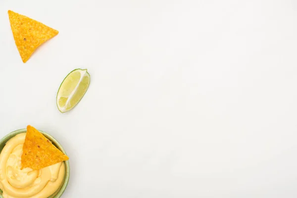 Vue du dessus des nachos de maïs avec sauce au citron vert et fromage sur fond blanc — Photo de stock