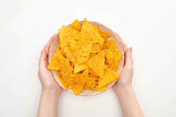 Vista recortada de la mujer sosteniendo tazón de nachos de maíz con sobre fondo blanco - foto de stock