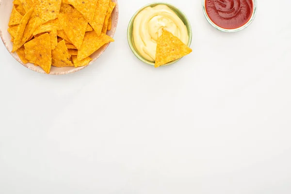 Top view of corn nachos with ketchup and cheese sauce on white background — Stock Photo