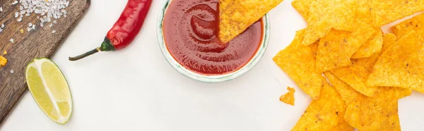 Vista superior de nachos de maíz con lima, chile, ketchup sobre fondo blanco, plano panorámico — Stock Photo