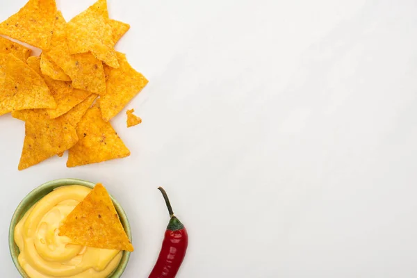 Vista superior de nachos de milho com molho de pimenta e queijo em tábua de corte de madeira no fundo branco — Fotografia de Stock