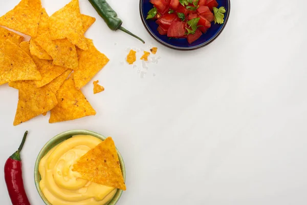 Vue du dessus des nachos de maïs avec sauce chili et fromage sur planche à découper en bois sur fond blanc — Photo de stock