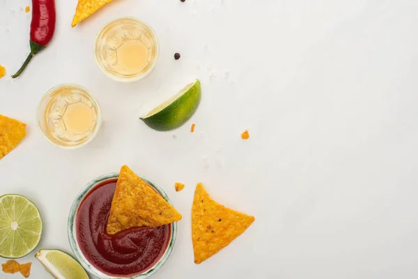 Top view of corn nachos with lime, chili, ketchup and tequila on white background — Stock Photo