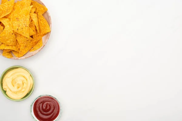 Vista superior de nachos de maíz con salsa de queso y ketchup sobre fondo blanco - foto de stock