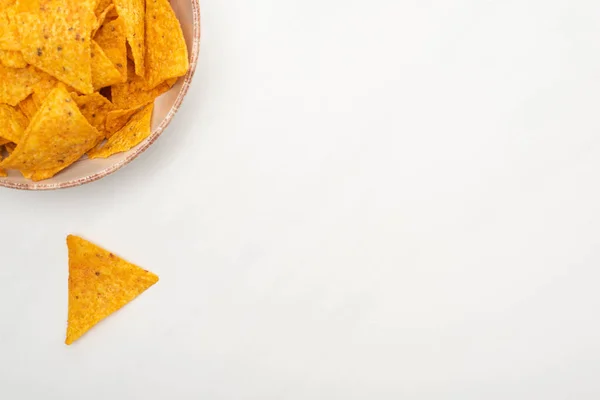 Vista superior de nachos de maíz crujientes en un tazón sobre fondo blanco - foto de stock