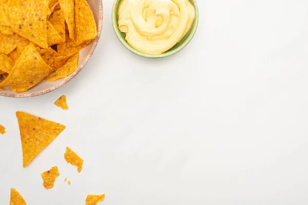 Vue du dessus des nachos de maïs avec sauce au fromage sur fond blanc — Photo de stock