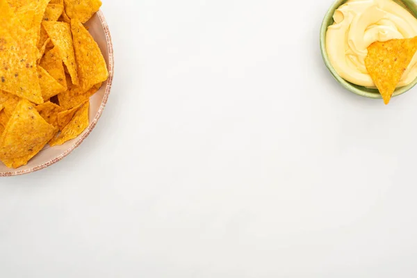 Vue du dessus des nachos de maïs avec sauce au fromage sur fond blanc — Photo de stock