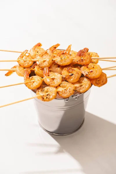 Crevettes sur brochettes sur seau métallique sur fond blanc — Photo de stock