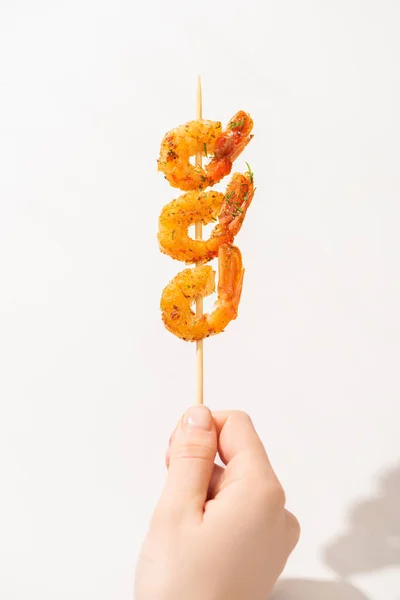 Vista recortada de la mujer sosteniendo gambas fritas sabrosas en pincho sobre fondo blanco - foto de stock