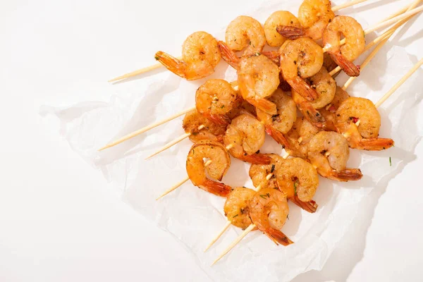 Top view of prawns on skewers on parchment paper on white background — Stock Photo