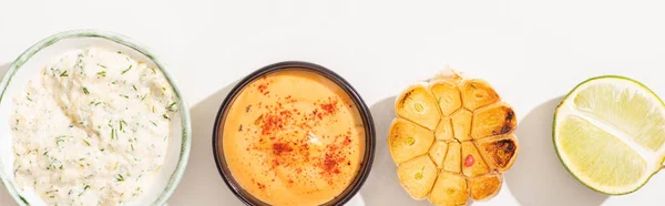 Top view of garlic, lime and sauces on white background, panoramic shot — Stock Photo