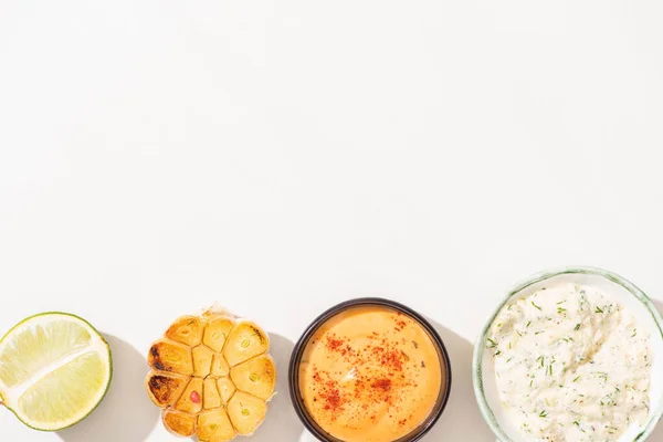 Vista superior de ajo, lima y salsas sobre fondo blanco - foto de stock