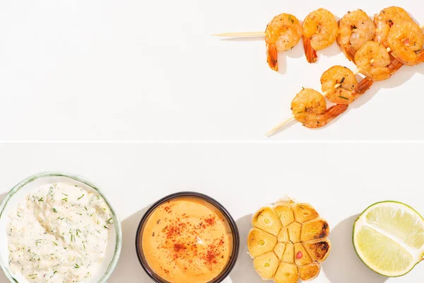 Collage de deliciosos langostinos fritos sobre pinchos con ajo, lima y salsas sobre fondo blanco - foto de stock