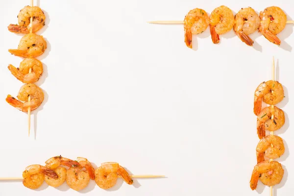 Vista superior de deliciosos langostinos fritos en brochetas sobre fondo blanco - foto de stock