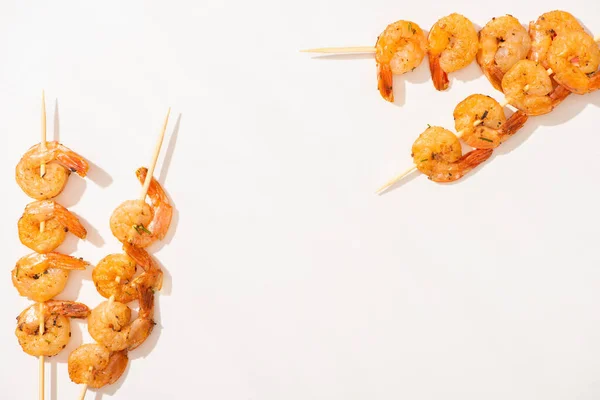 Vista superior de deliciosos langostinos fritos en brochetas sobre fondo blanco - foto de stock