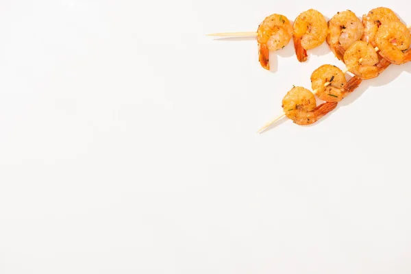 Vue de dessus de délicieuses crevettes frites sur brochettes sur fond blanc — Photo de stock