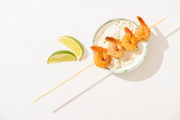 Top view of delicious fried prawns on skewer with lime and sauce on white background — Stock Photo