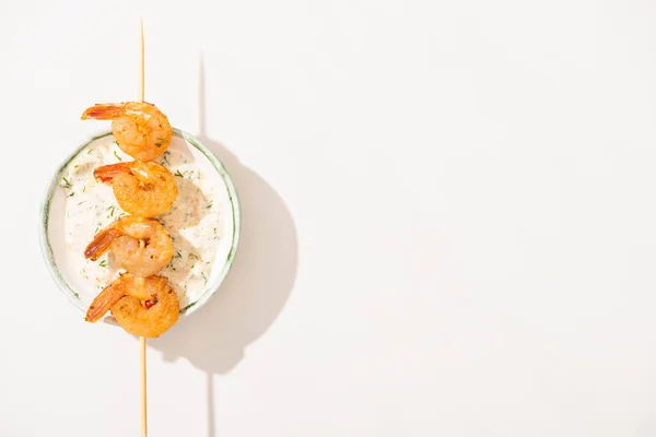 Vista superior de deliciosos langostinos fritos en pincho con salsa sobre fondo blanco - foto de stock