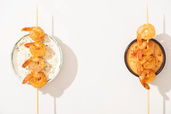 Top view of delicious fried prawns on skewers with sauces on white background — Stock Photo