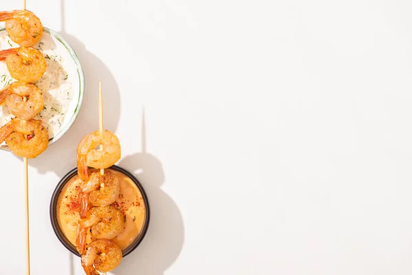 Top view of delicious fried prawns on skewers with sauces on white background — Stock Photo