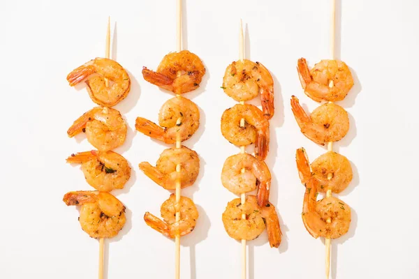 Vue de dessus de délicieuses crevettes frites sur brochettes sur fond blanc — Photo de stock