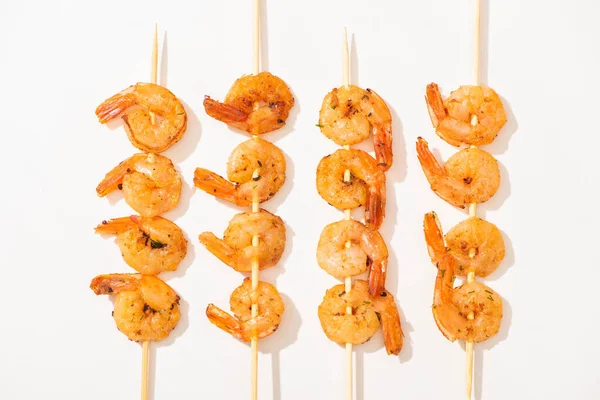 Vista superior de deliciosos langostinos fritos en brochetas sobre fondo blanco - foto de stock